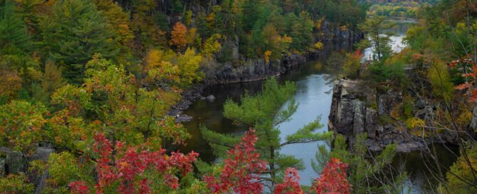 a beautiful landscape scene of the Mississippi River with trees beginning to change to autumn colors.