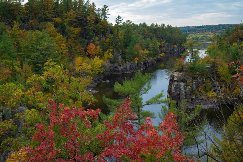 a beautiful landscape scene of the Mississippi River with trees beginning to change to autumn colors.